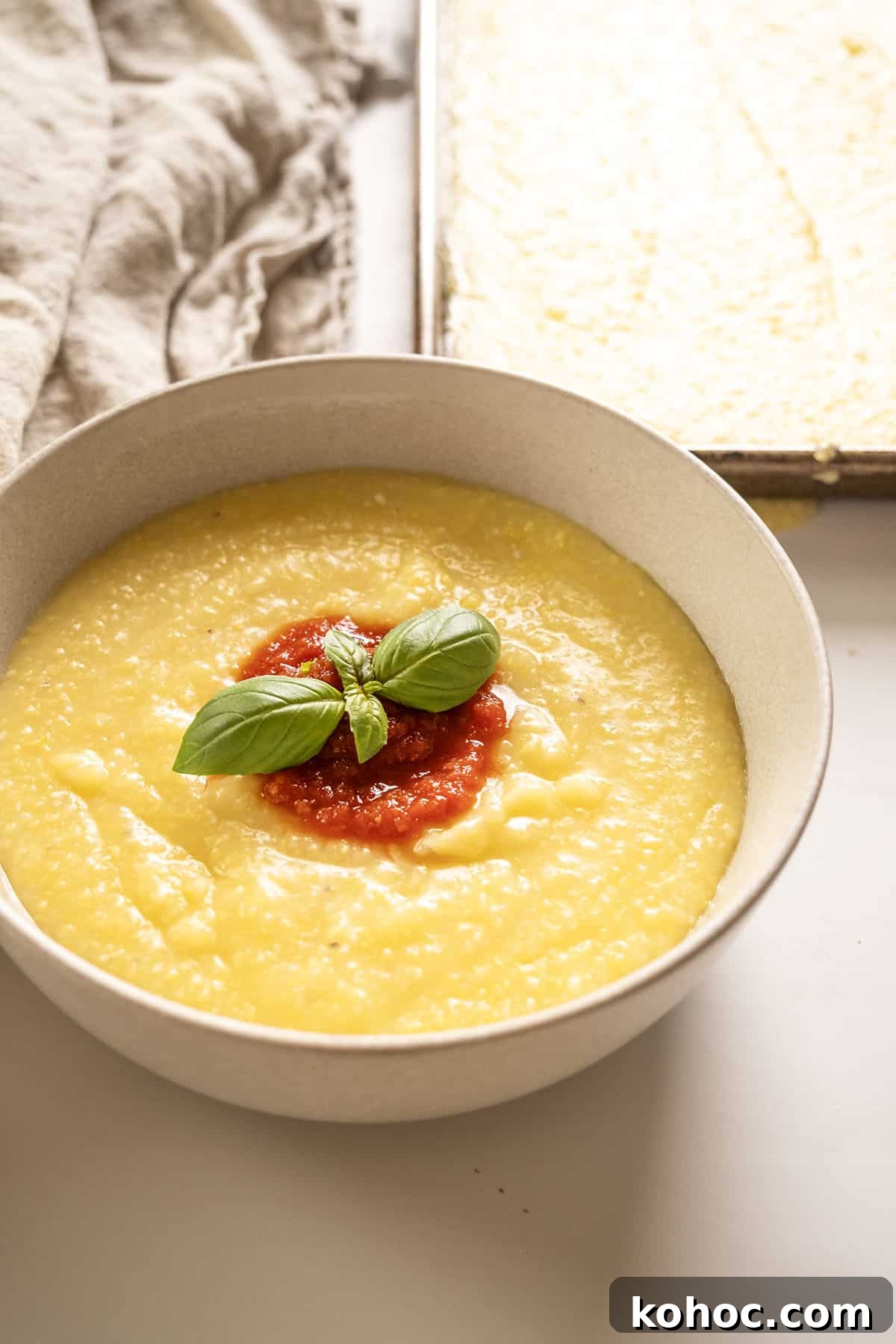 Creamy Italian Polenta Recipe 2 Creamy polenta in a bowl topped with marinara and basil.