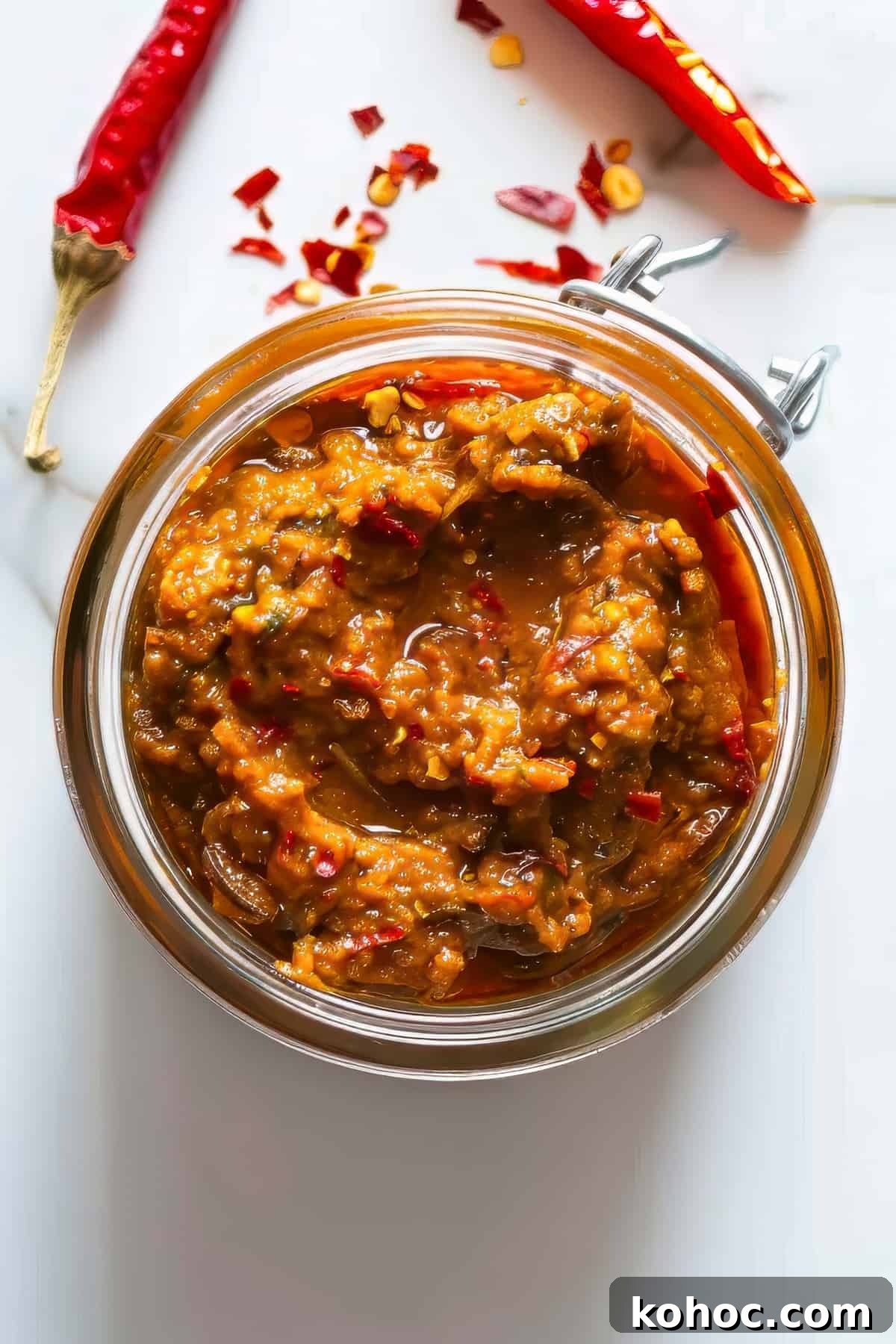 Homemade Thai red curry paste in a jar on a white table.