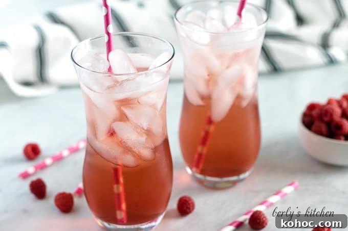 Two glasses of raspberry italian soda with pink straws.