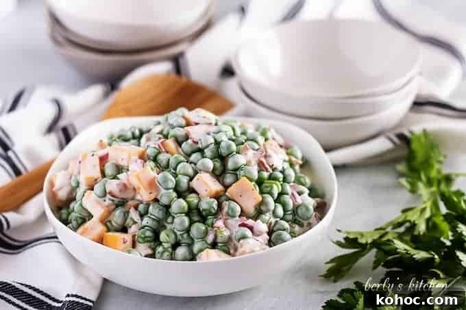 The pea salad served in a large bowl with a wooden spoon.