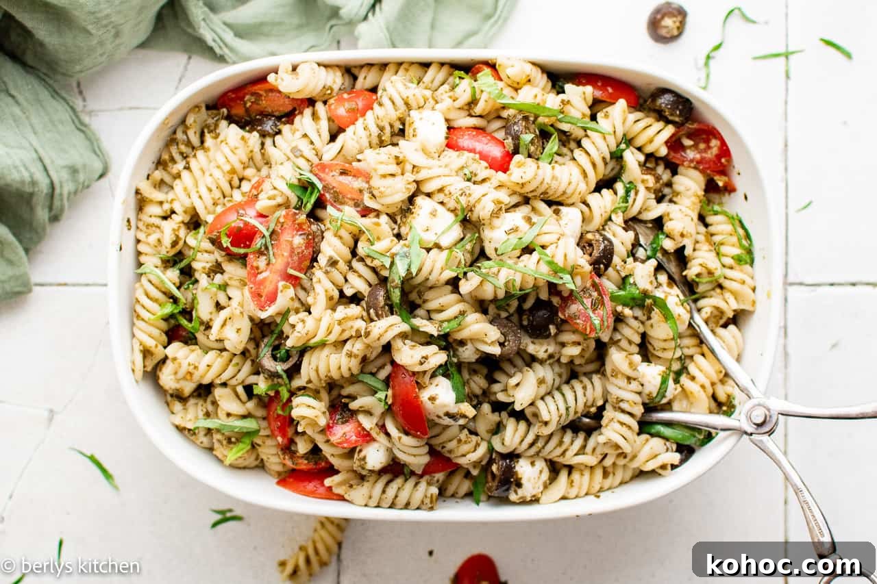 Top down view of pasta salad in a large serving dish with serving spoon.