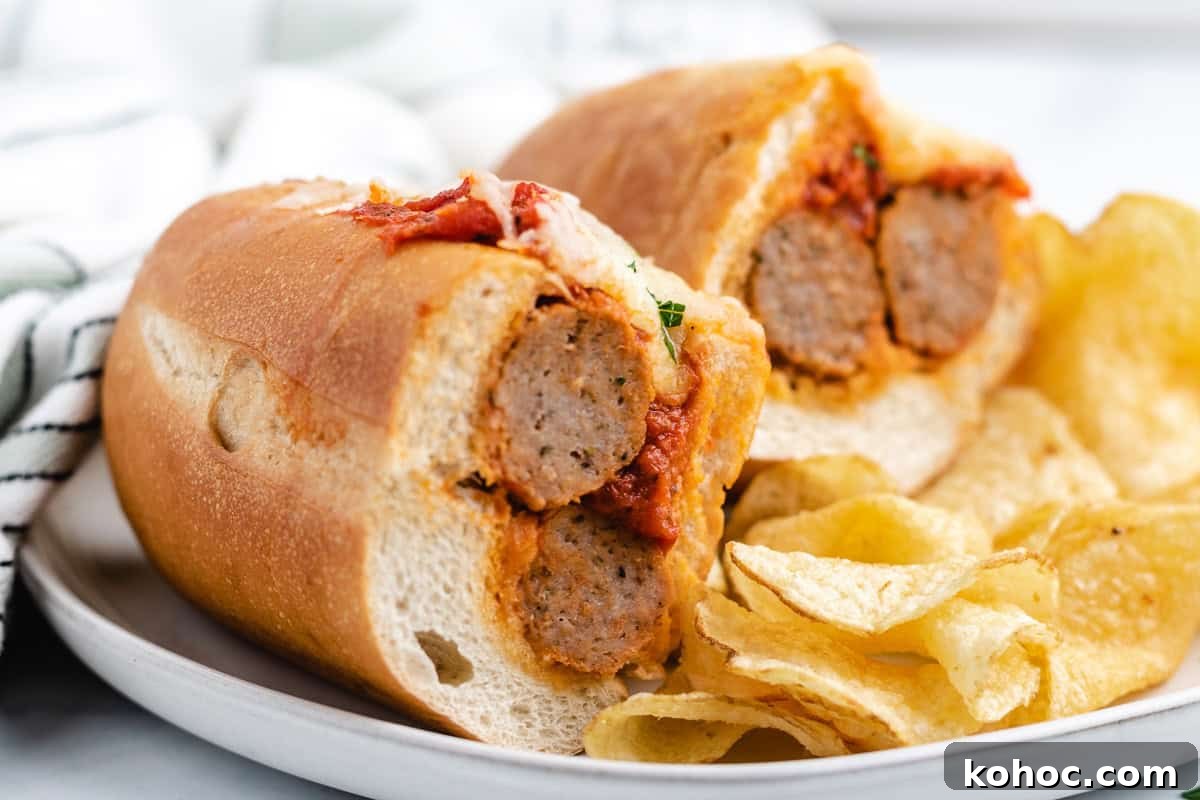 Meatball sub cut in half next to potato chips.