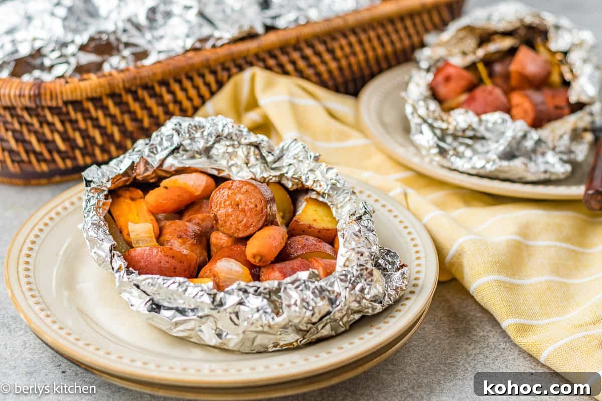 Sausage, potato, and carrots foil packet on a plate.