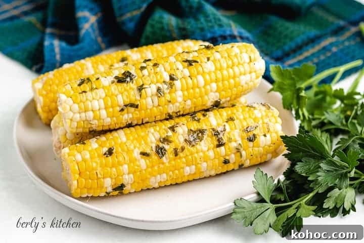 Four pieces of grilled corn on the cob on a plate.