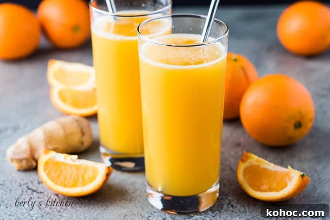Fizzy orange drinks next to fresh oranges.