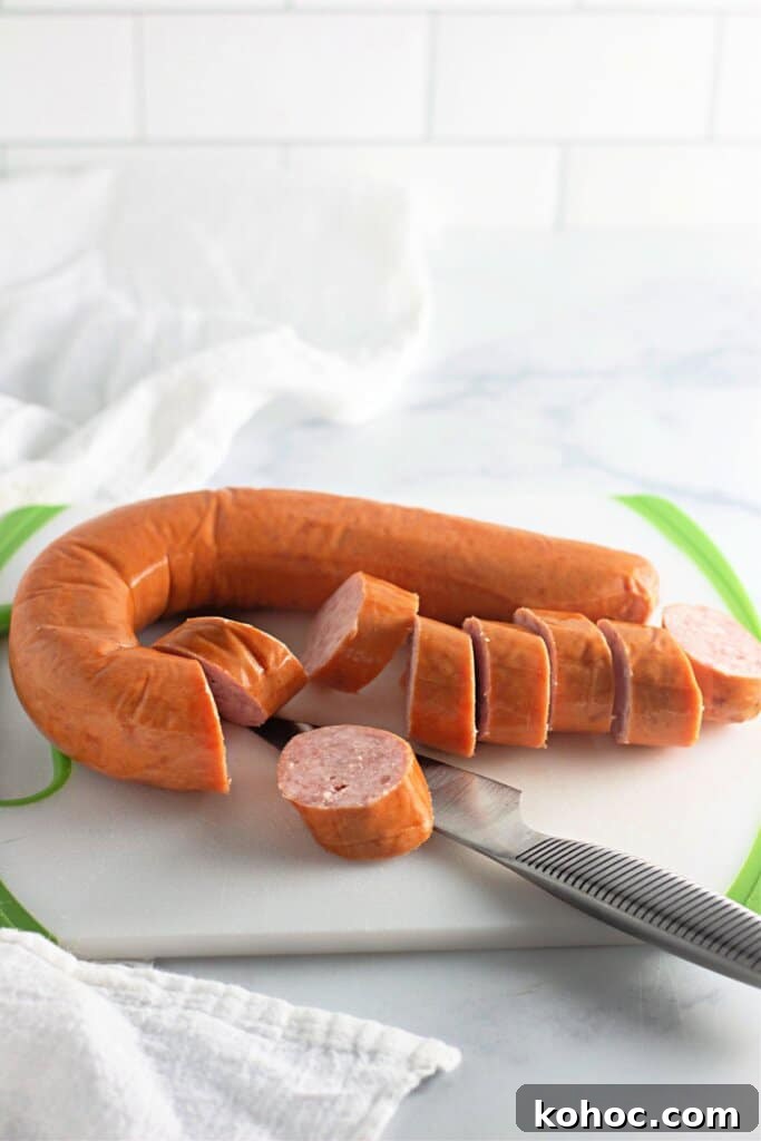 Oven-Baked BBQ Kielbasa Roast: Sweet Glazed Sausage Recipe 5 Smoked sausage being sliced on a cutting board.