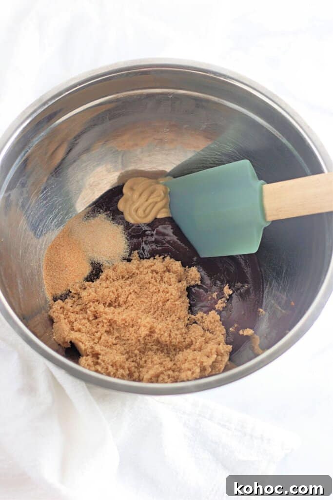 Oven-Baked BBQ Kielbasa Roast: Sweet Glazed Sausage Recipe 6 Sauce ingredients in a stainless steel mixing bowl being mixed with a rubber spatula.