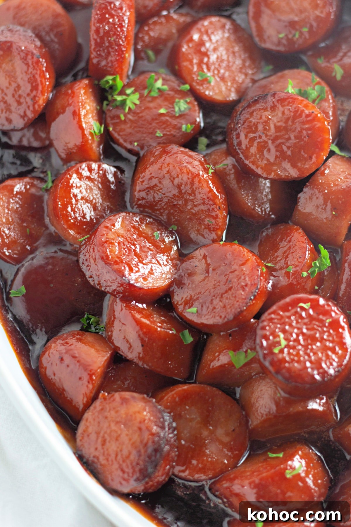 Oven-Baked BBQ Kielbasa Roast: Sweet Glazed Sausage Recipe 10 White bowl full of baked bbq kielbasa.