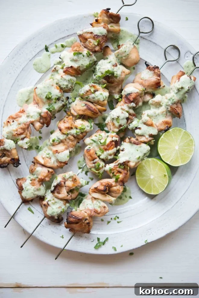 Citrus Chicken with Cilantro-Garlic Sauce Recipe 2 overhead view of skewers of Citrus Chicken with Cilantro Garlic Sauce on a white plate