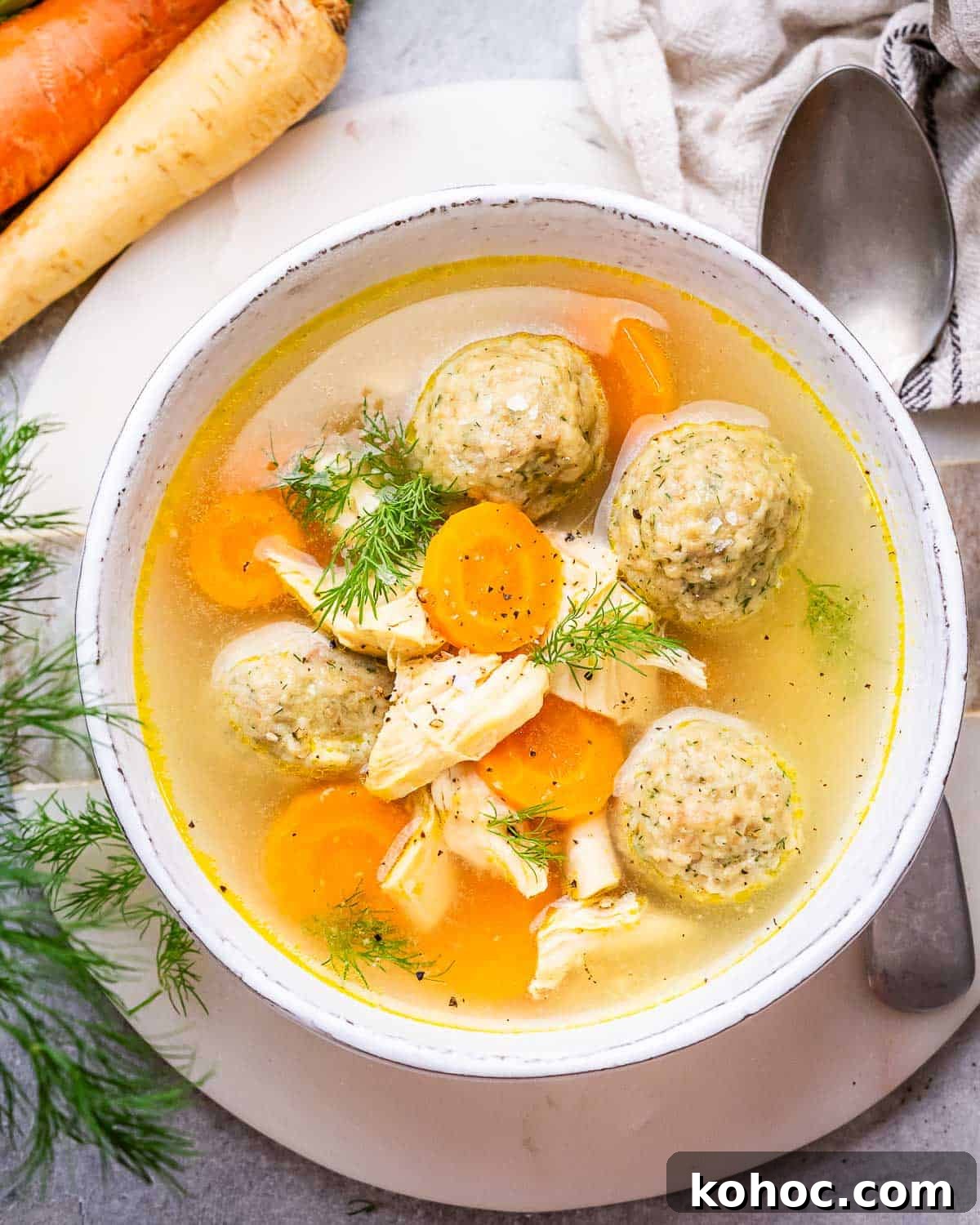 Classic Matzo Ball Soup Recipe: Cozy Homemade Comfort Soup 2 A white bowl of matzo ball soup with a spoon