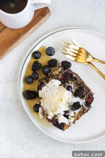 Overhead view of a piece of baked berry oatmeal with coconut whipped cream and syrup on top