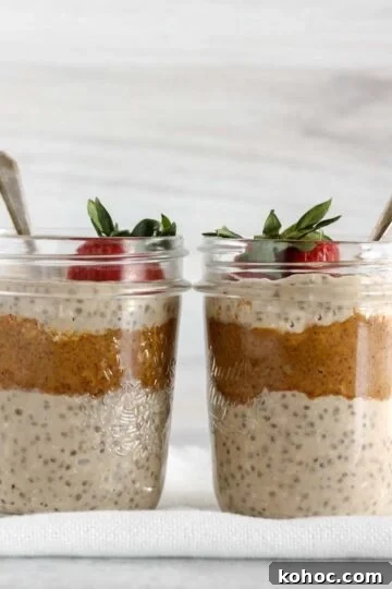 Two mason jars filled with overnight oats and almond butter topped with a strawberry.