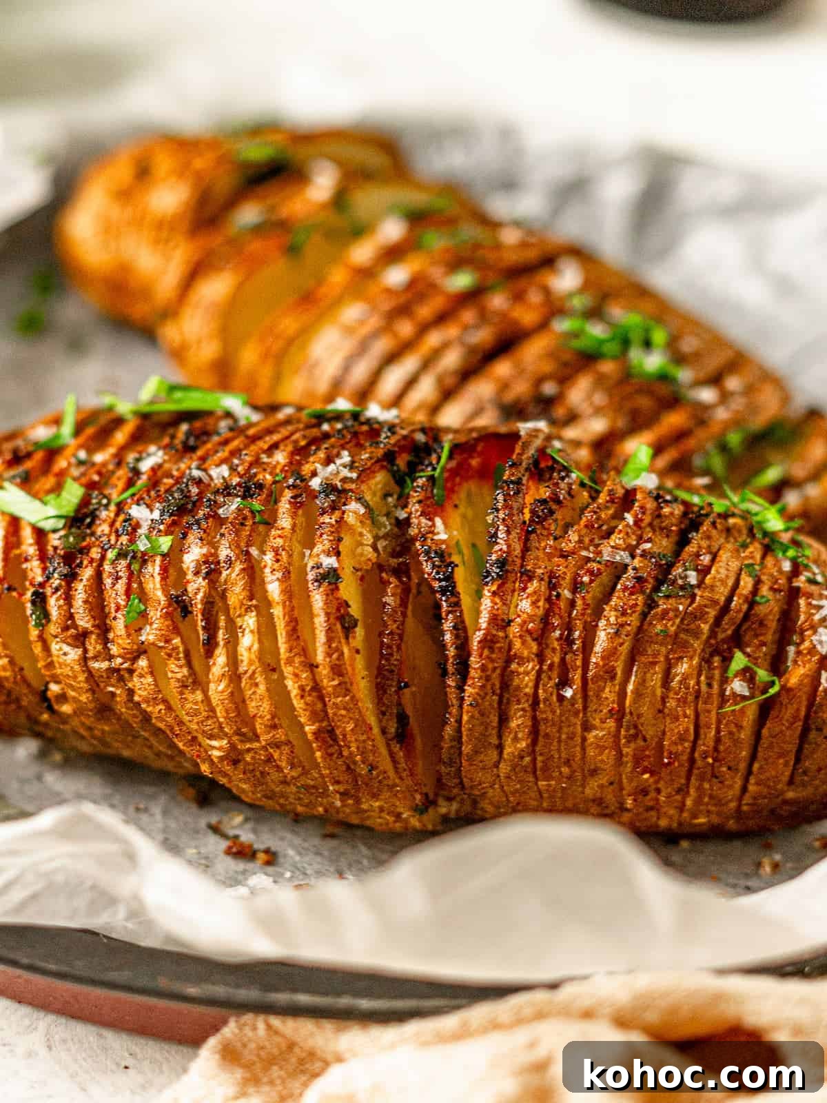 Crispy Air Fryer Hasselback Potatoes with Garlic and Herbs 2 Sliced hasselback potatoes seasoned with parsley.