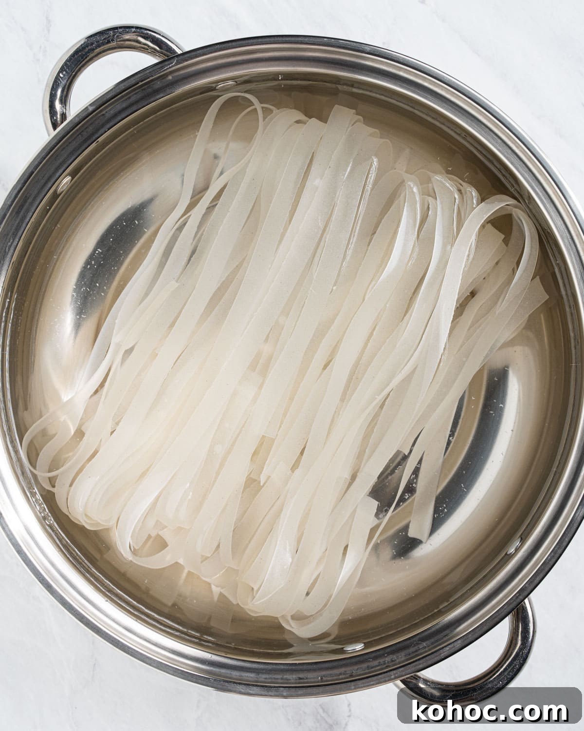 Perfect Rice Noodles: How to Cook Them Without Overcooking 11 extra large rice noodles boiling in a pot of water.