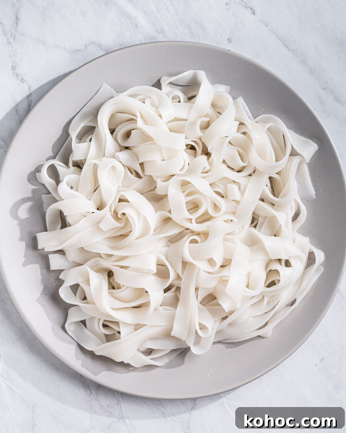 Perfect Rice Noodles: How to Cook Them Without Overcooking 12 Cooked flat extra large wide rice noodles on a plate.