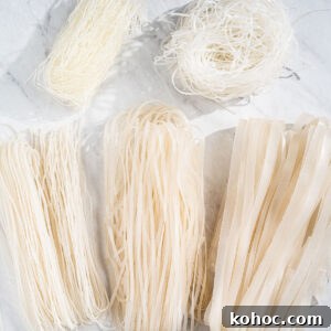 5 different types of rice noodles on a marble surface. There's thin vermicelli, thick vermicelli, fresh rice noodles (pho), dried medium flat rice noodles, and dried extra large flat rice noodles.