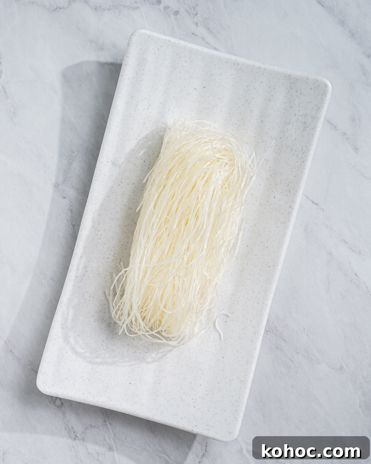 Perfect Rice Noodles: How to Cook Them Without Overcooking 7 uncooked dried vermicelli on a rectangle plate.