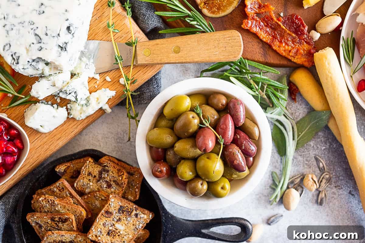Autumn Cheese Board Ideas for Entertaining 4 Gorgonzola cheese, seeds cracker, and olives on a table.
