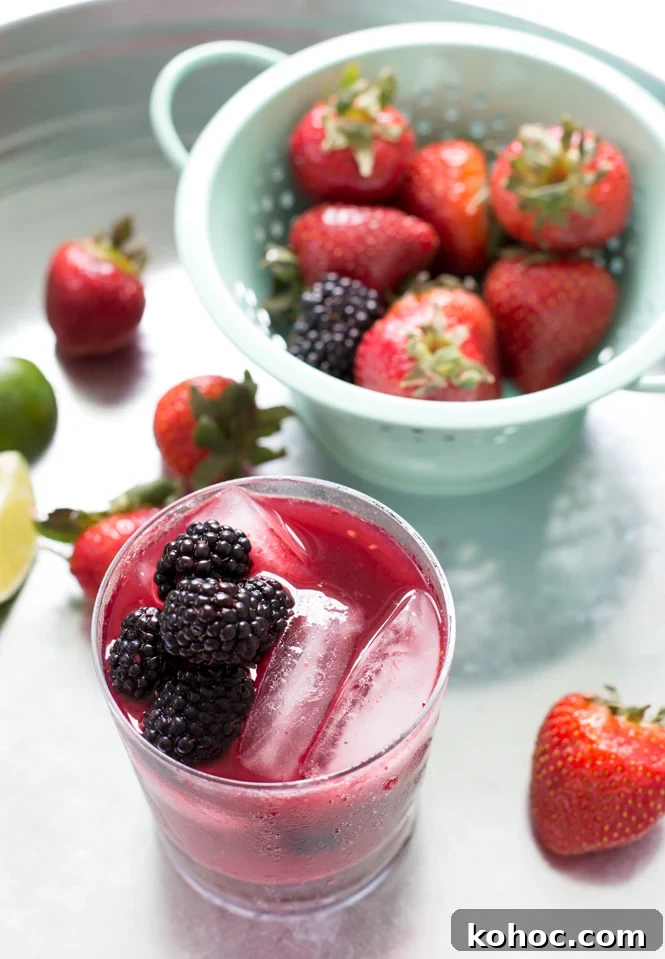 Mixed Berry Mojito Recipe: Refreshing Berry Mint Cocktail 2 Mixed Berry Mojito in glass with colander of berries in background