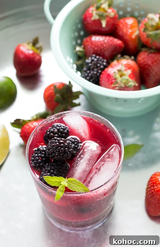 Mixed Berry Mojito Recipe: Refreshing Berry Mint Cocktail 3 close up of Mixed Berry Mojito garnished with mint, berries scattered on table