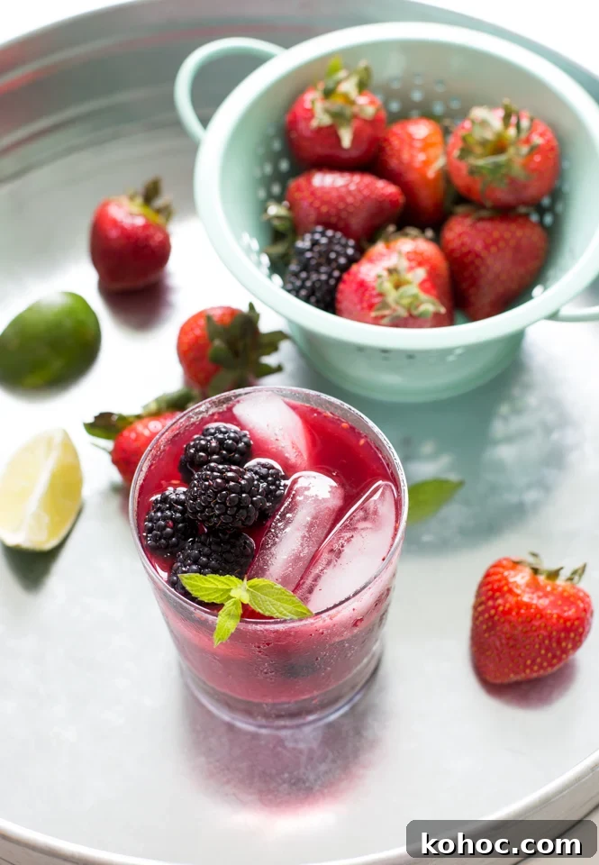 Mixed Berry Mojito Recipe: Refreshing Berry Mint Cocktail 4 close up of Mixed Berry Mojito garnished with mint, berries and lime scattered on table, colander in background