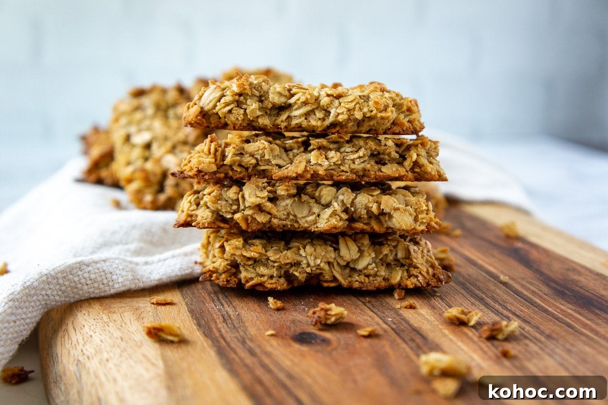 Baked Nut-Free Granola Bars Recipe 2 a stack of baked granola bars on a wooden cutting board.