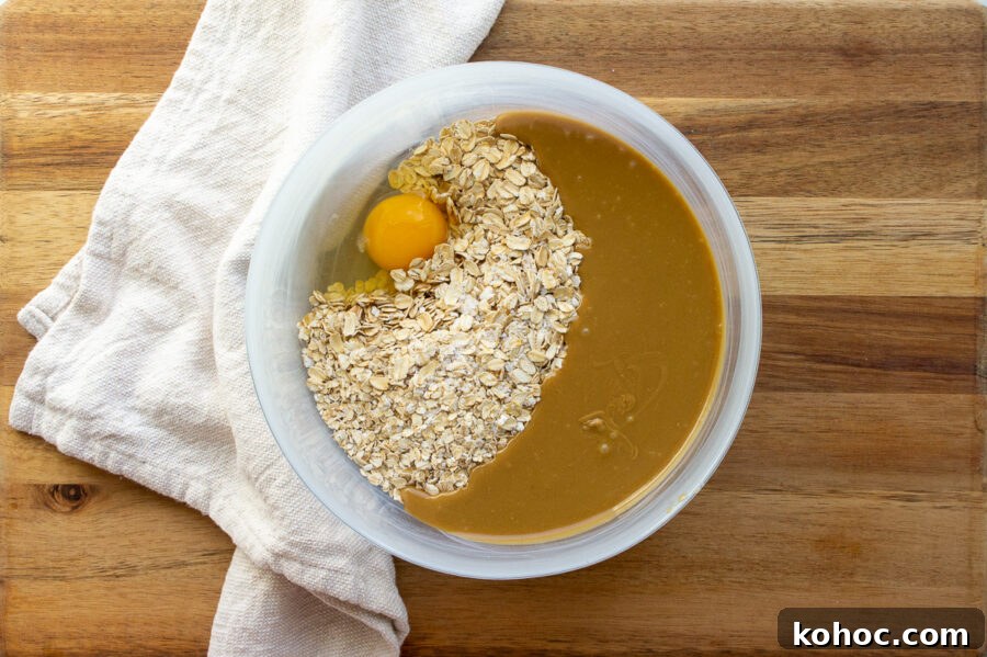Baked Nut-Free Granola Bars Recipe 4 oats, an egg, and melted honey with butter and sunflower seed butter in a bowl.