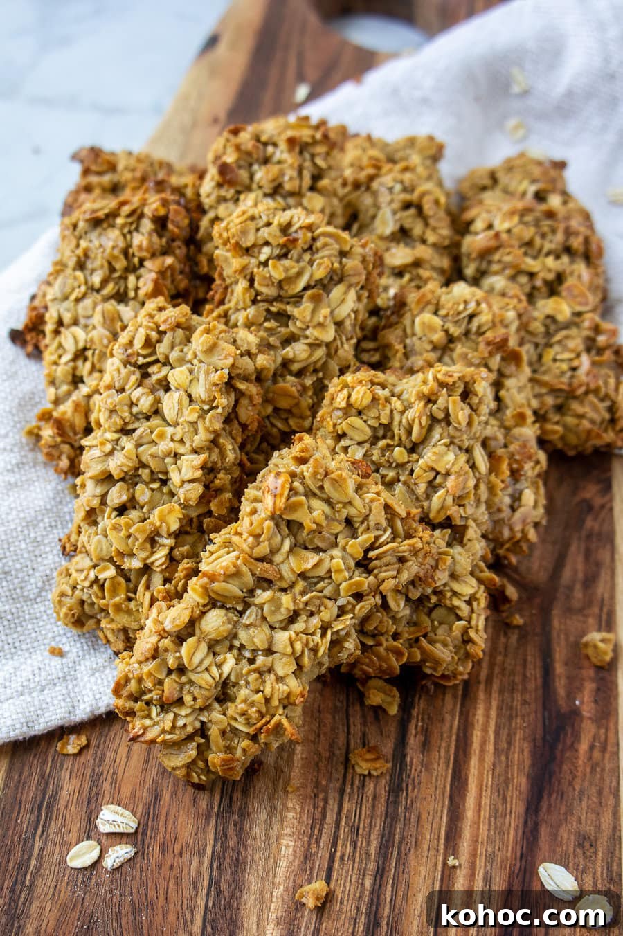 Baked Nut-Free Granola Bars Recipe 7 a bunch of granola bars on a wooden cutting board with a beige towel.