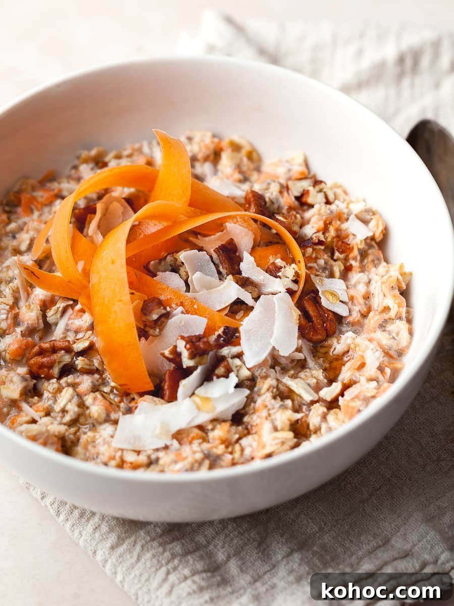 a bowl of gluten free carrot cake overnight oats topped with carrot ribbons, coconut chips and pecans