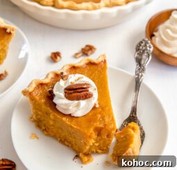 white round plate with slice of sweet potato pie garnished with whipped cream and pecan with fork taking bite