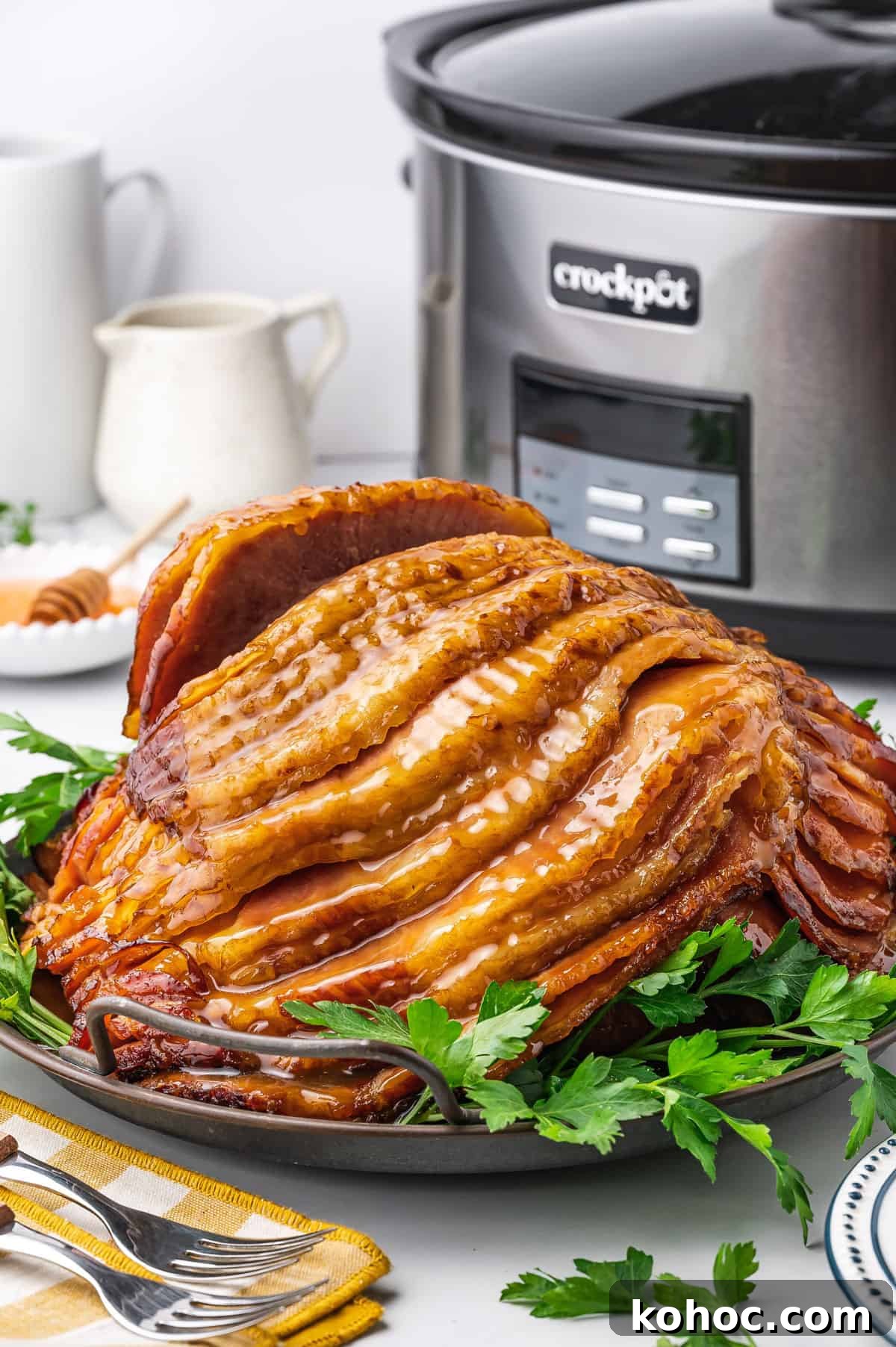 Slow Cooker Ham with Brown Sugar Glaze 8 A platter with a slow cooker ham with a crockpot in the background.