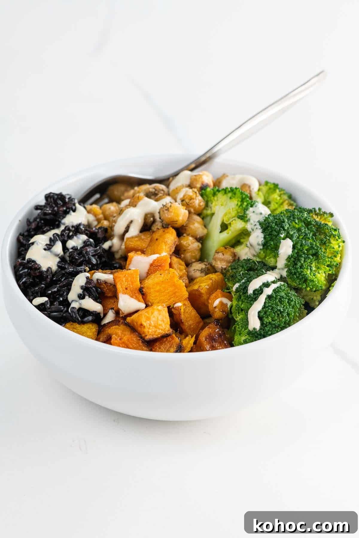 a black rice bowl with maple roasted butternut squash, sauteed chickpeas, broccoli, and tahini dressing