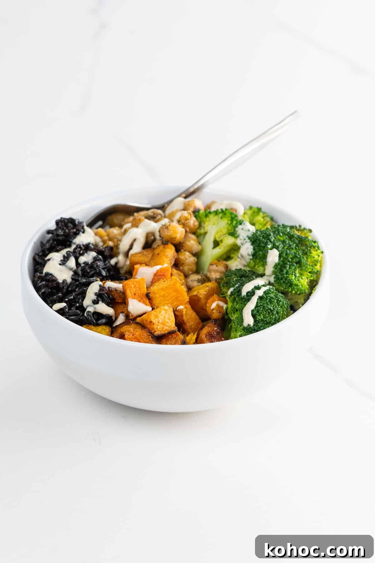 a black rice bowl with maple roasted butternut squash, sauteed chickpeas, broccoli, and tahini dressing