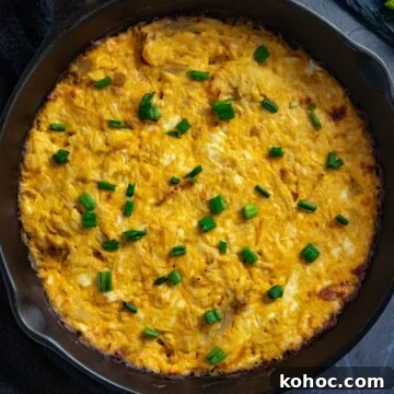Baked dip topped with sliced green onions in a skillet.