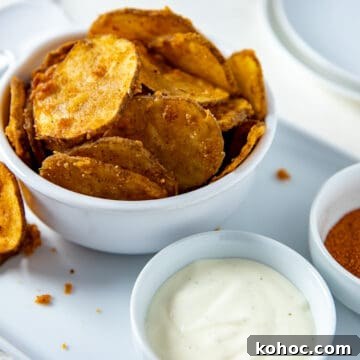 White bowl filled with fried potato slices plus a small bowl of ranch dressing on the side.