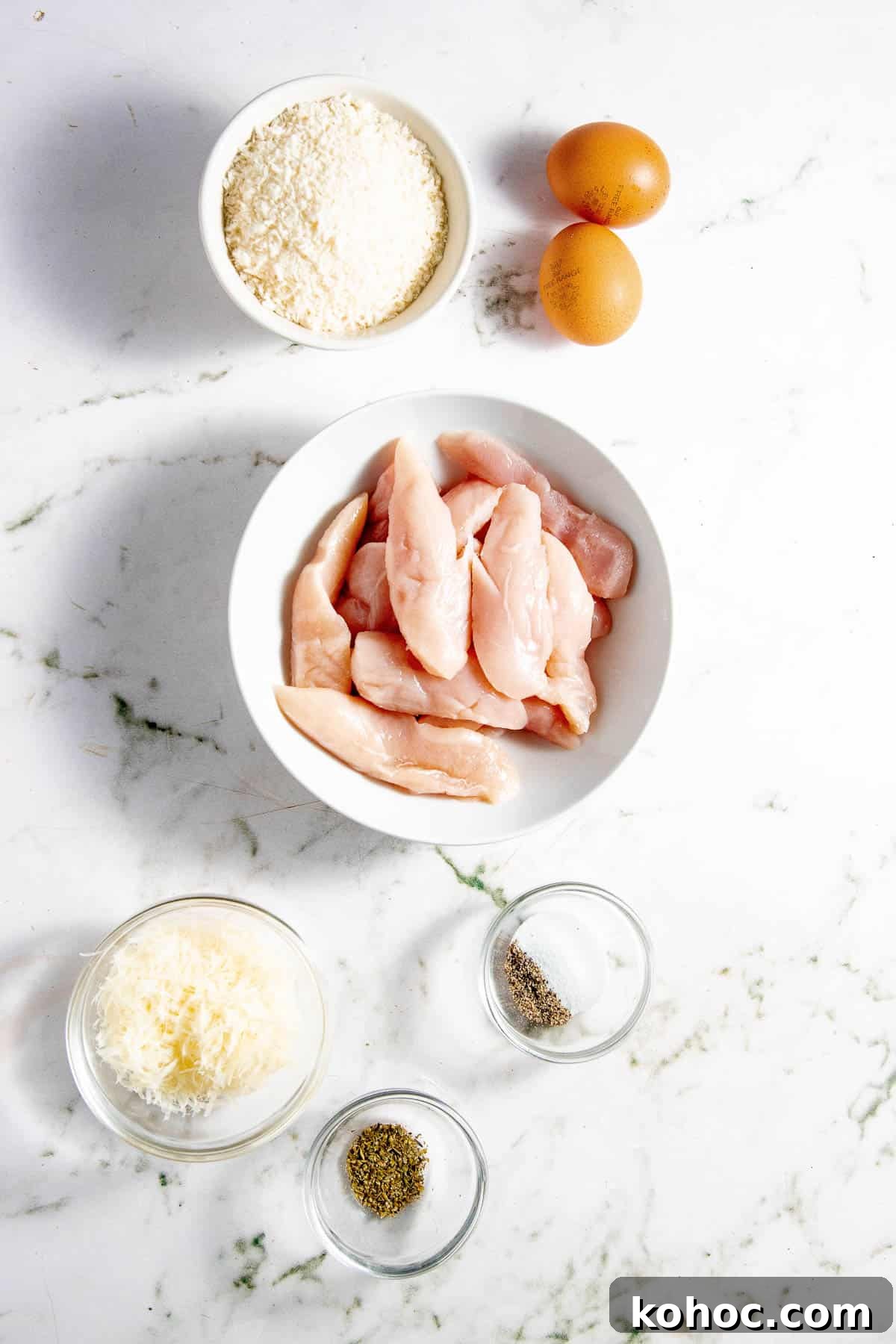 The ingredients for chicken tenders in the air fryer on a marble table.