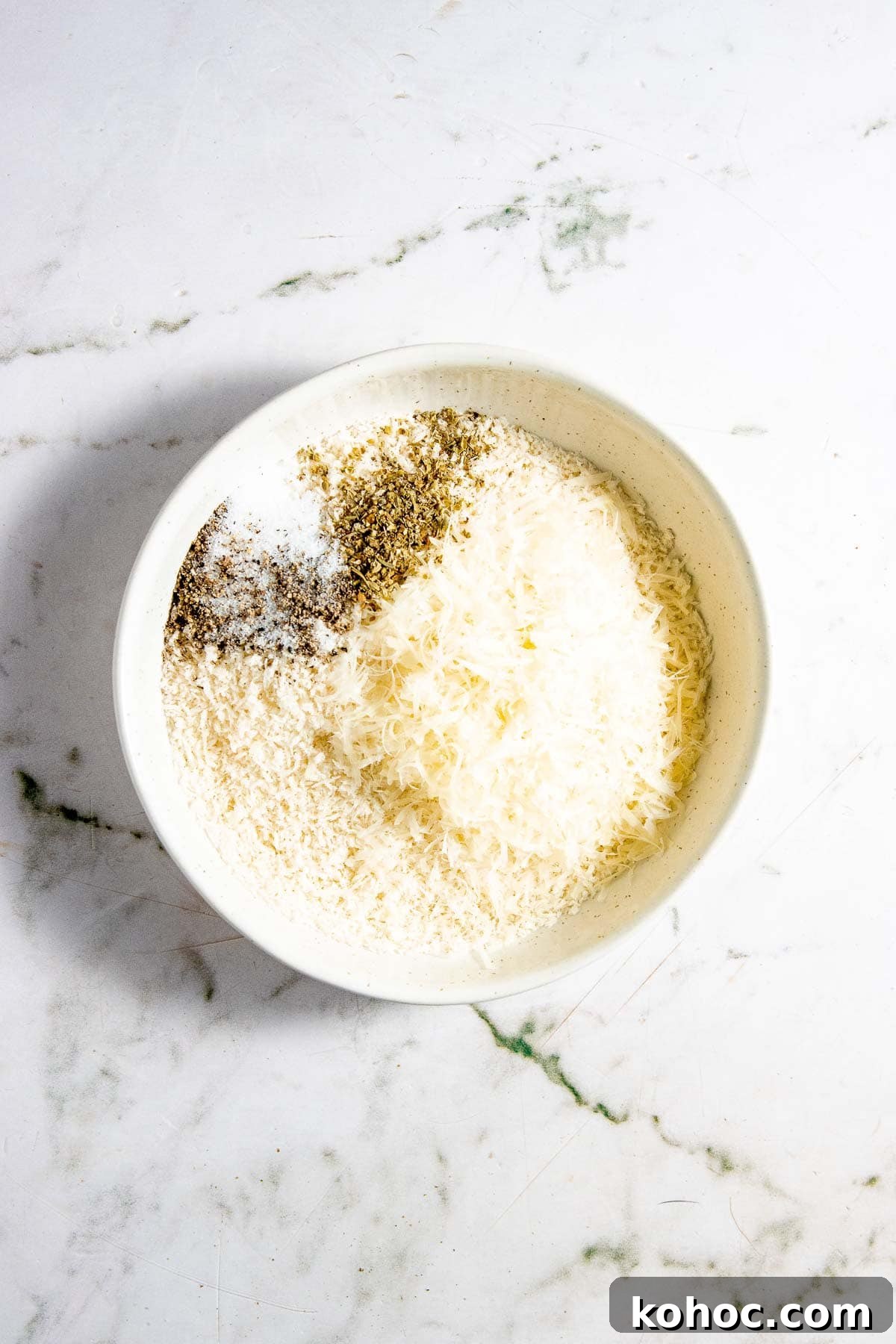 A bowl of panko and spices on a marble table.