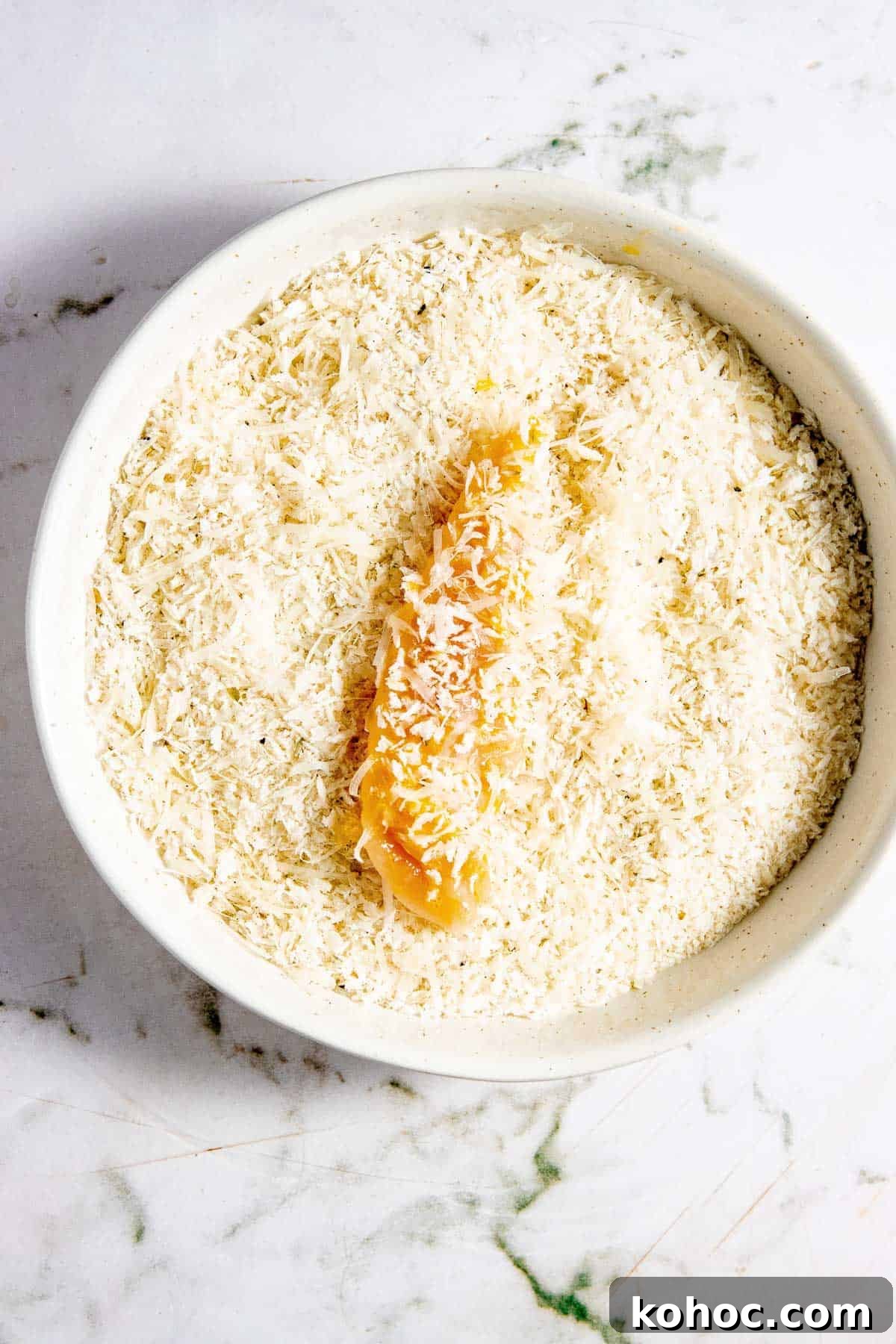 A bowl of panko with a chicken tender in it.