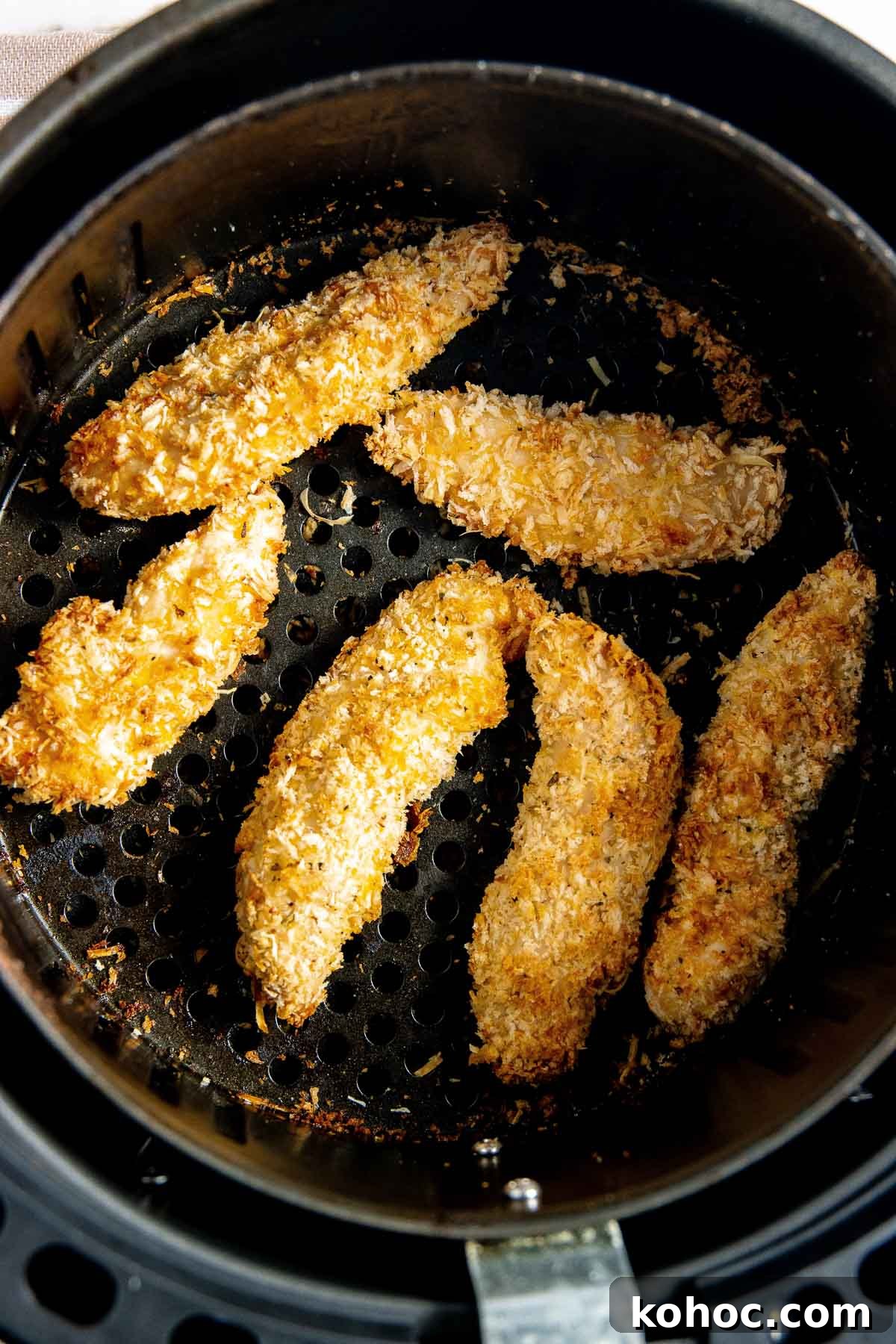 Chicken strips in an air fryer basket.