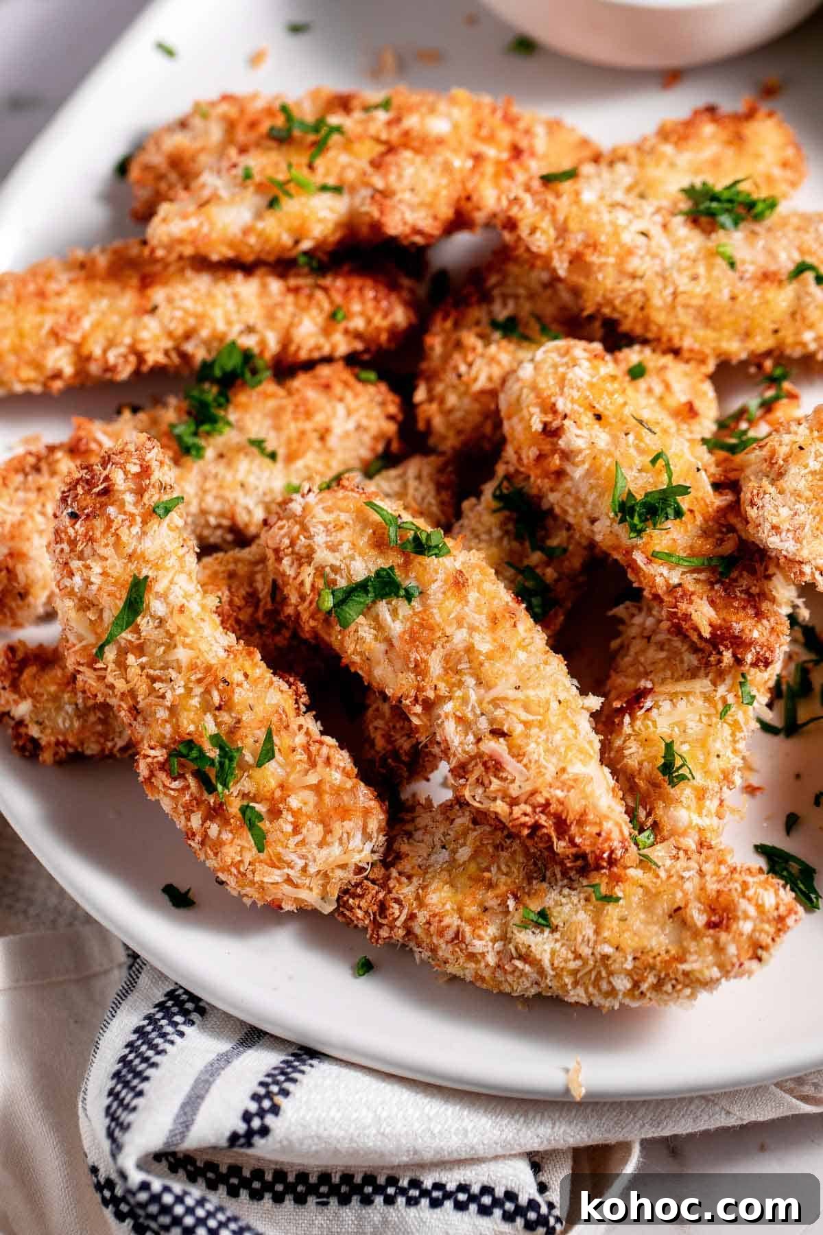 Air fryer chicken tenders on a plate with dipping sauce.