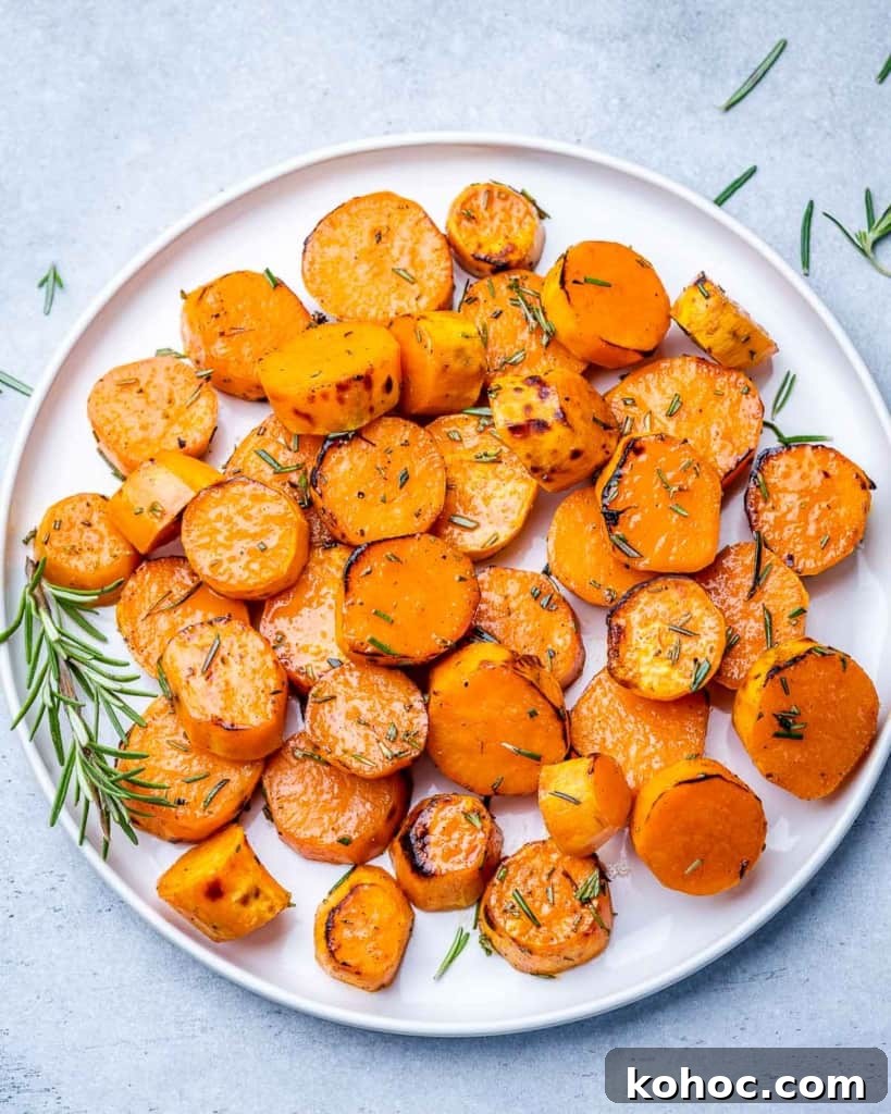 Crispy Roasted Sweet Potatoes with Garlic and Herbs 2 Roasted sweet potatoes on a white plate garnished with a sprig of rosemary.