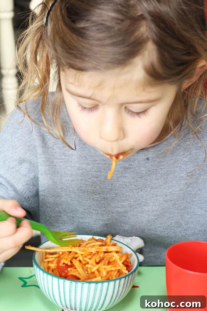 Tomato Spaghetti Kids Will Love 4 child eating a bowl of simple tomato spaghetti
